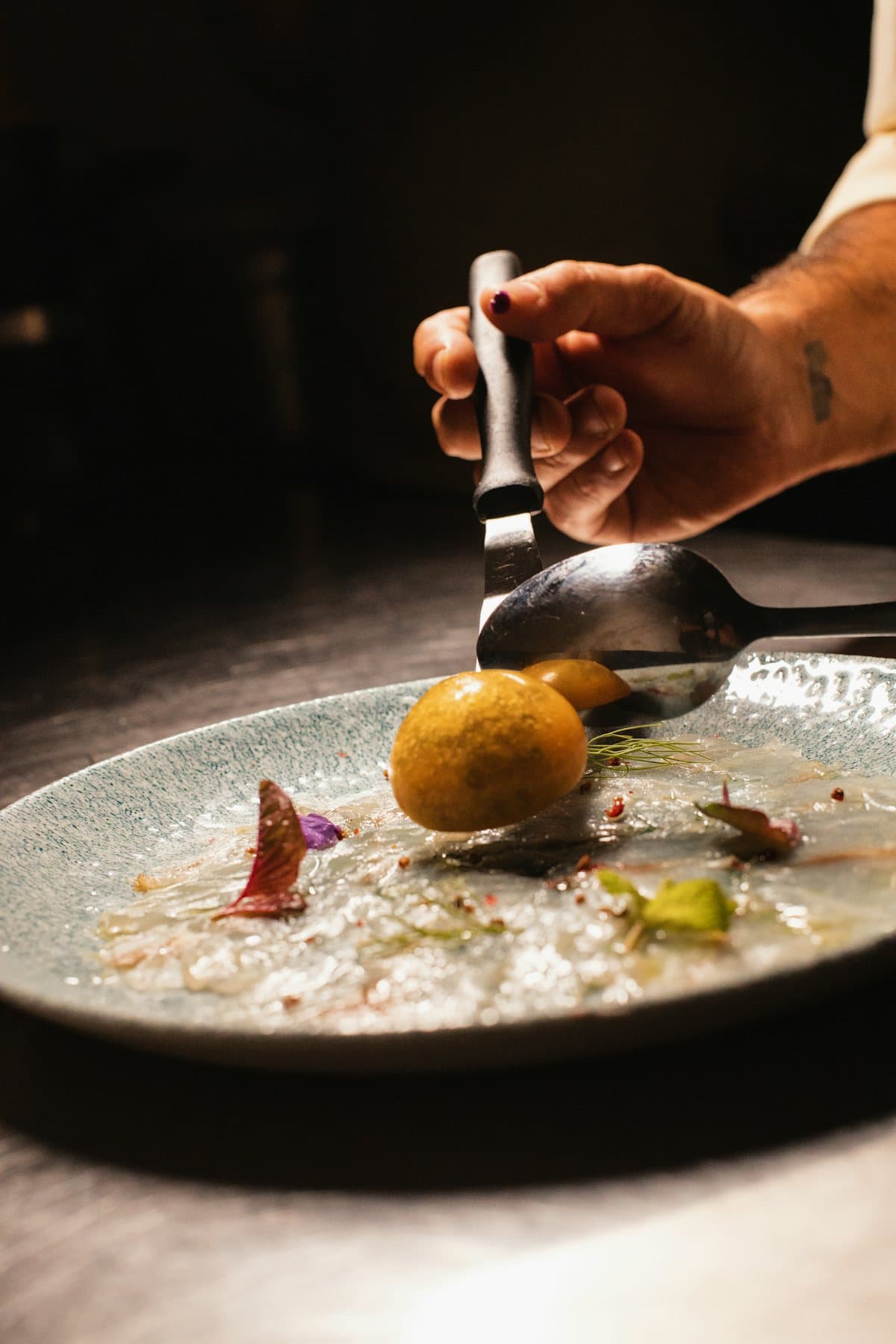 Une main dépose une sphère dorée sur une assiette à la cuillère