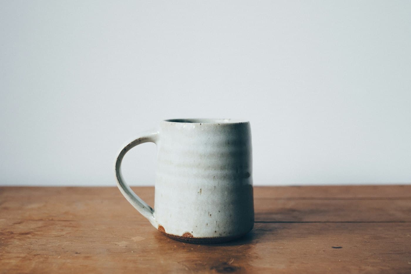 Mug à l'émail bleu-gris posé sur une table en bois sombre