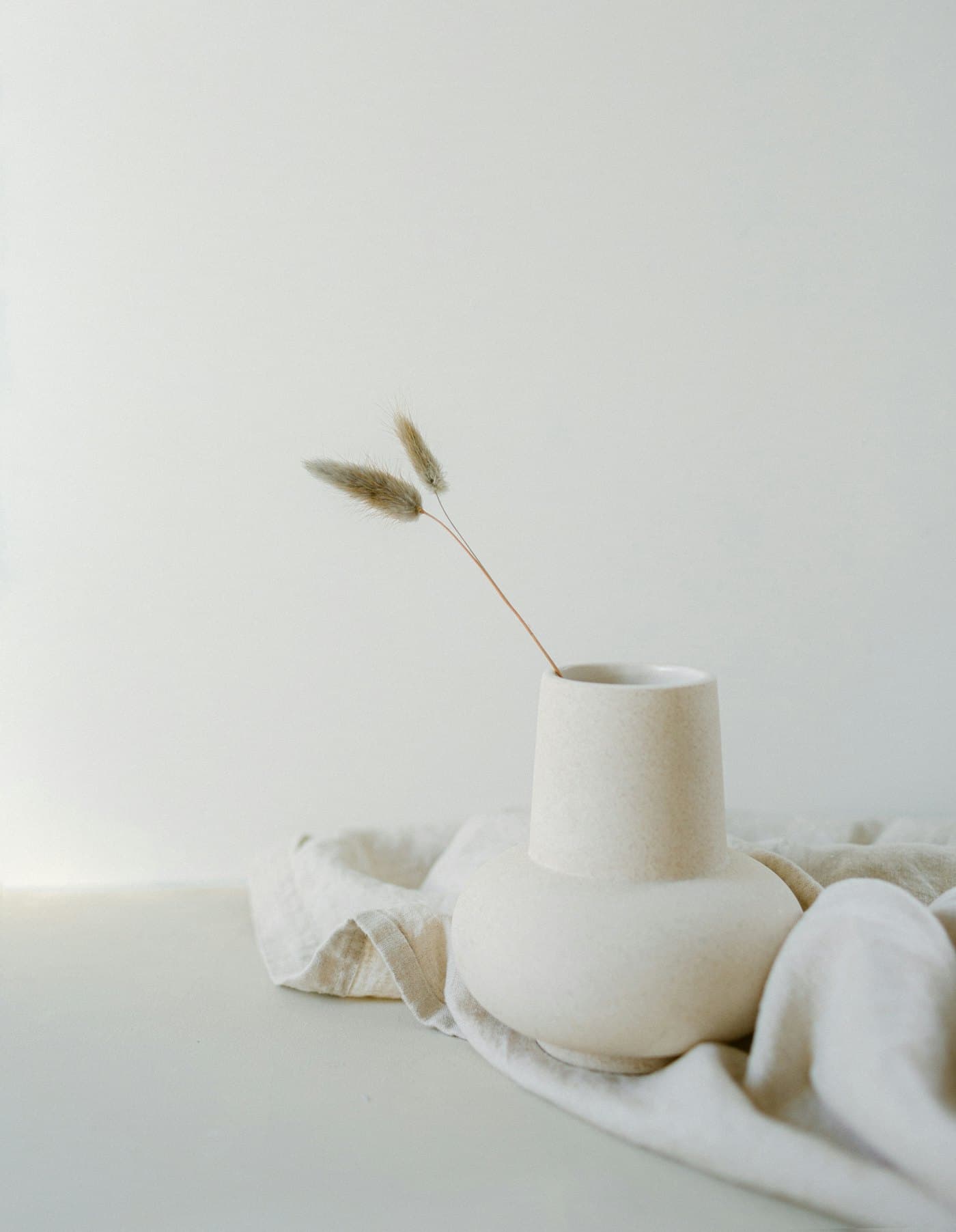 Soliflore blanc avec une tige séchée, posé sur un linge écru