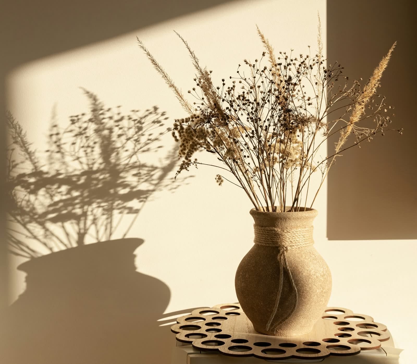 Le vase Hegoa, en grès brut, avec un bouquet de fleurs séchées dans la lumière du soir