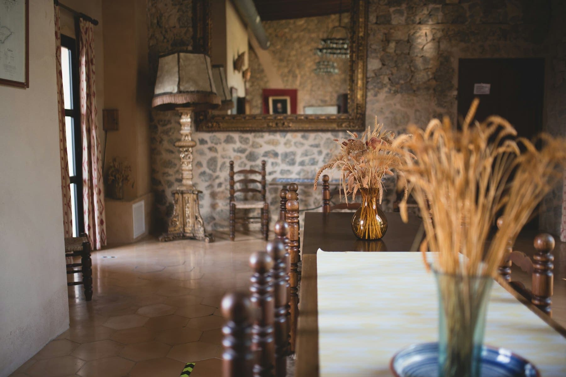 Longue table en châtaignier et chaises tournées, dans une salle aux murs de pierre et au sol de tomettes