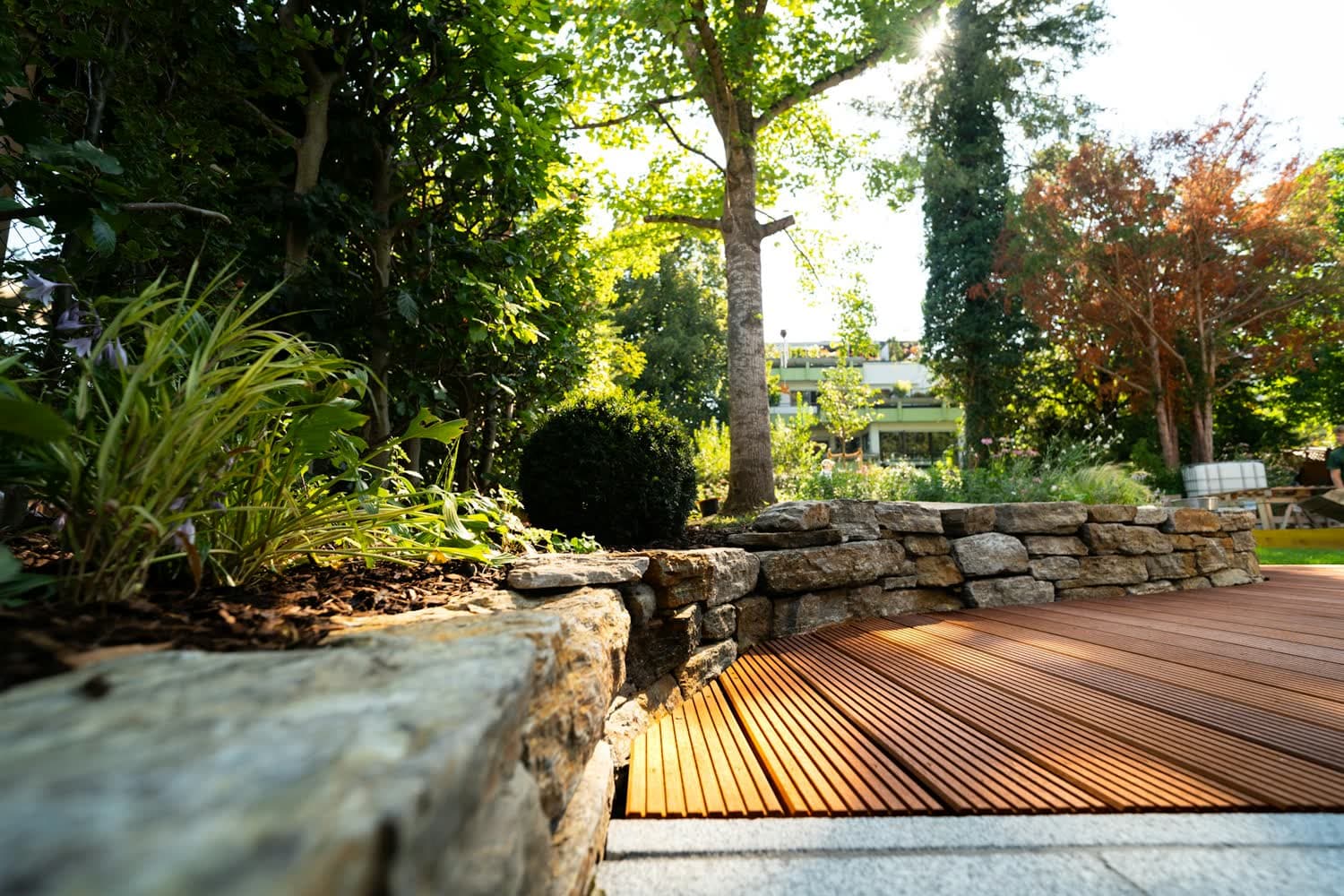 Une terrasse en bois bordée d'un muret de pierre sèche et de graminées