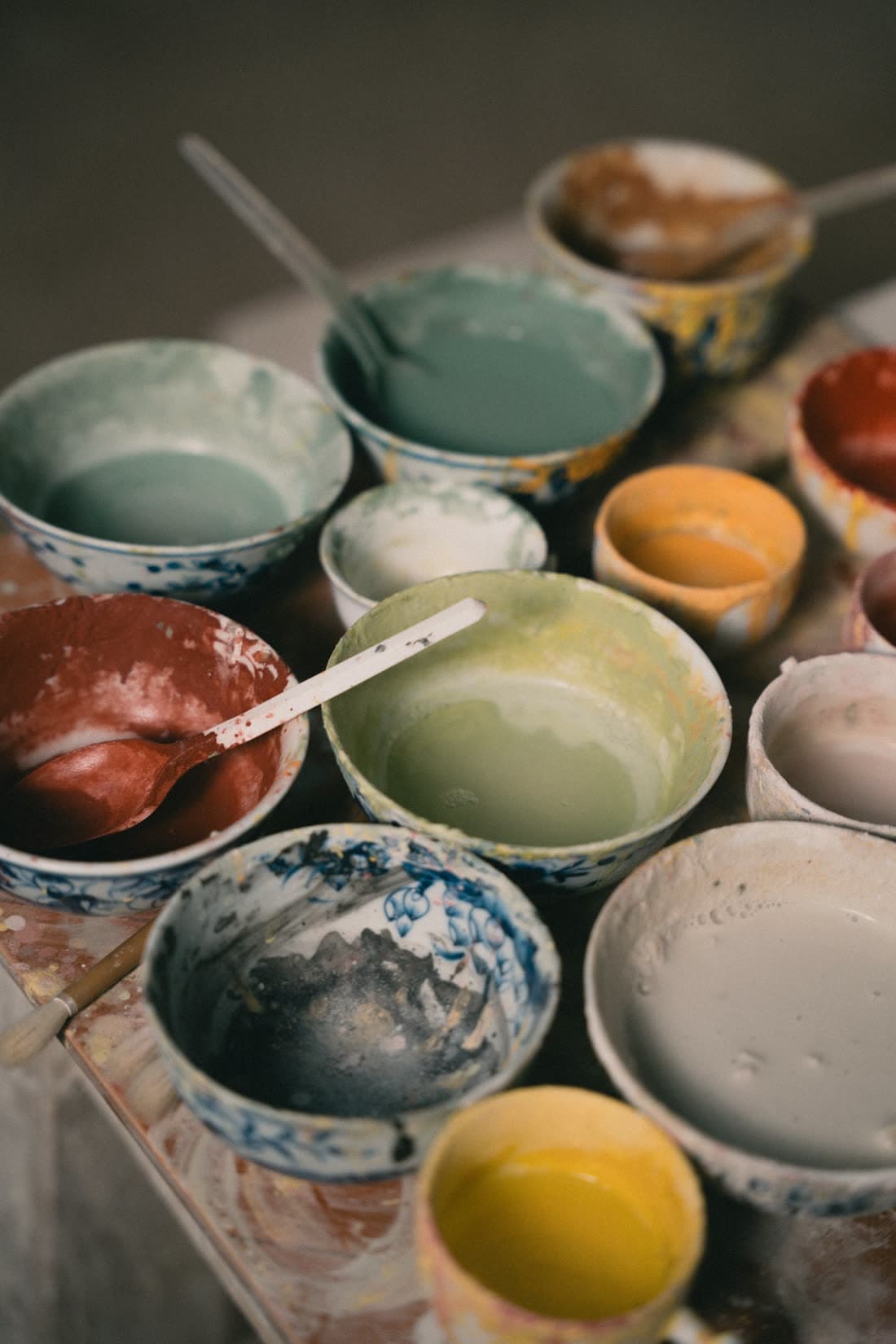 Des bols remplis d'émaux de couleur, crème, céladon, rouille et jaune, prêts à l'emploi